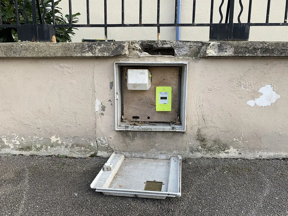 Compteur Linky vert dans un coffret ouvert encastré dans un mur, dans une rue de Lyon