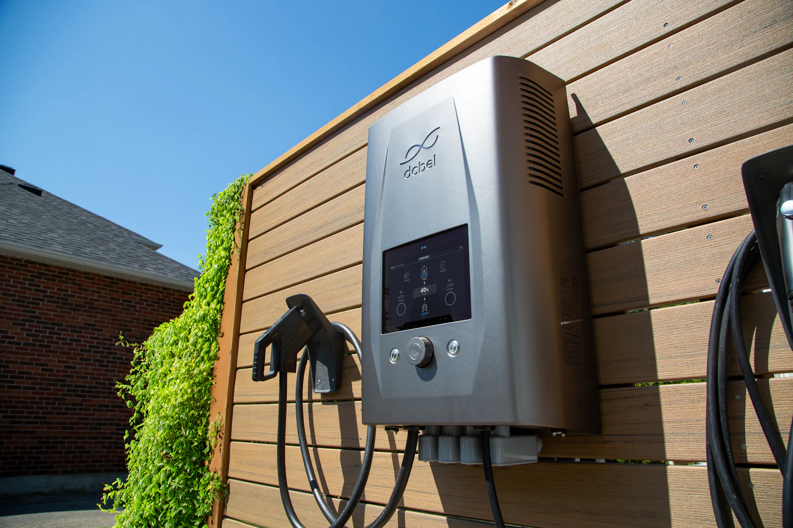 Borne de recharge murale installée sur une façade en bois